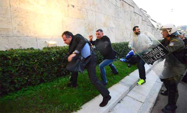 O deputado da Nova Democracia, Giorgos Koumoutsakos, escapa aos agressores sob o olhar da polícia em frente ao parlamento.